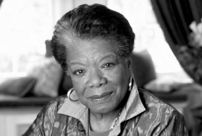 A black-and-white portrait of an elderly woman with short, styled hair, wearing a patterned blouse and hoop earrings, looking directly at the camera with a slight smile.