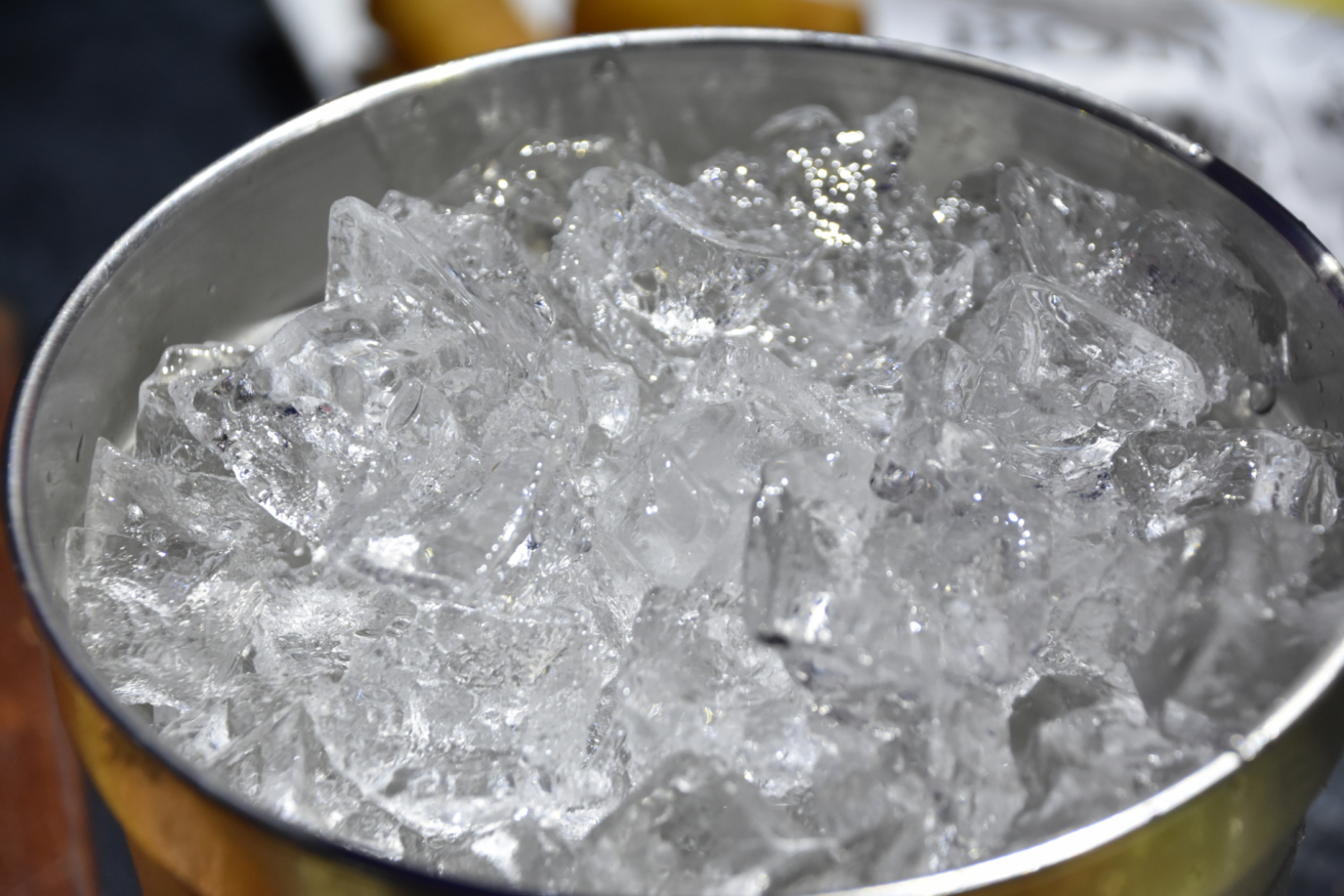 A metal bowl filled with clear ice cubes.