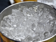 A metal bowl filled with clear ice cubes.