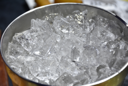 A metal bowl filled with clear ice cubes.