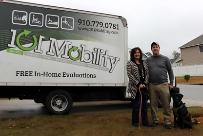 A man and woman stand with a dog in front of a 101 Mobility truck, which offers free in-home evaluations for mobility products.