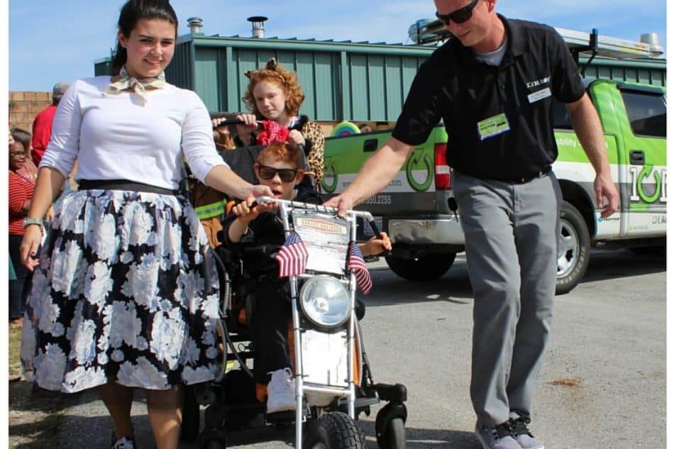 kid on biker design wheelchair with parents 