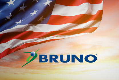 An American flag waves beside a sunset sky with the word "BRUNO" and a green and blue logo beneath it.