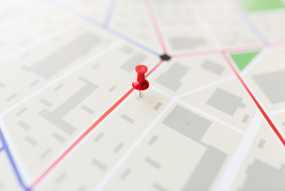 A red pushpin is placed on a map, marking a specific location. The map shows various streets and blocks in a light color scheme.