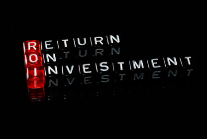 Red and clear letter dice spelling "ROI" vertically and "Return On Investment" horizontally on a black background.