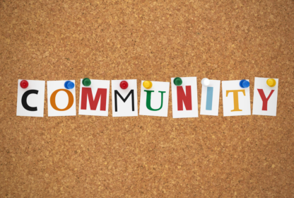 The word "COMMUNITY" is spelled out using colorful letters pinned to a corkboard.