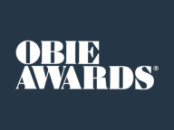 White text reading "OBIE AWARDS" displayed on a dark blue background.