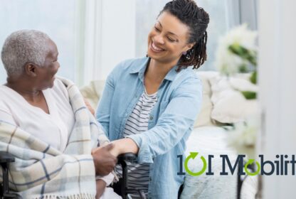 A caregiver helps an elderly person in a wheelchair. Both are smiling at each other. A logo for "101 Mobility" is visible in the bottom right corner.