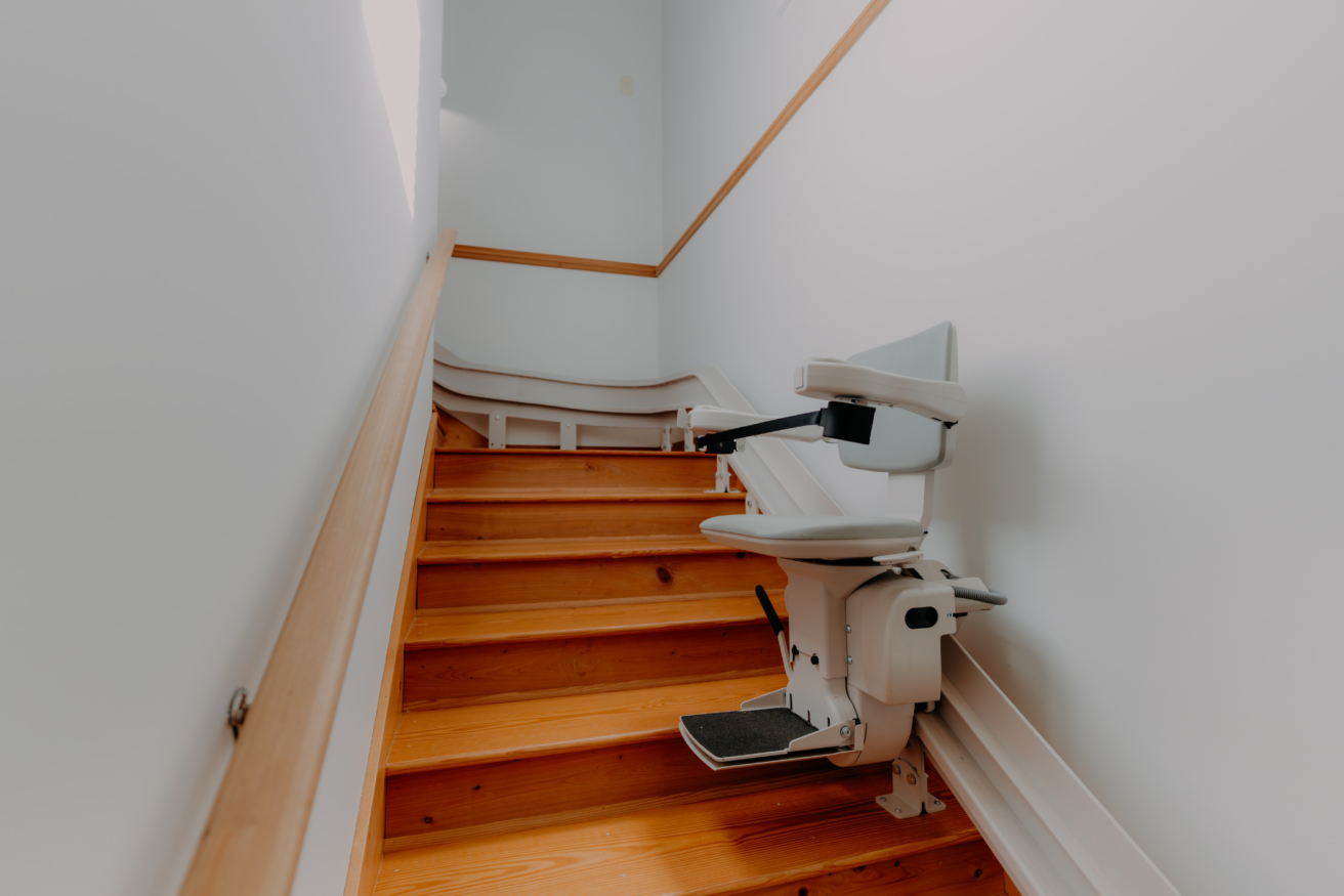 A stair lift is installed along the wooden steps of a staircase to aid in mobility.