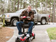 a person using a 4-wheel golden technologies power scooter outdoors.