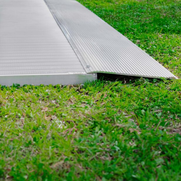 A metal accessibility ramp installed on a grassy area.