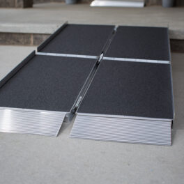 A portable folding ramp with a non-slip surface is laid out on a concrete floor, ready for use.