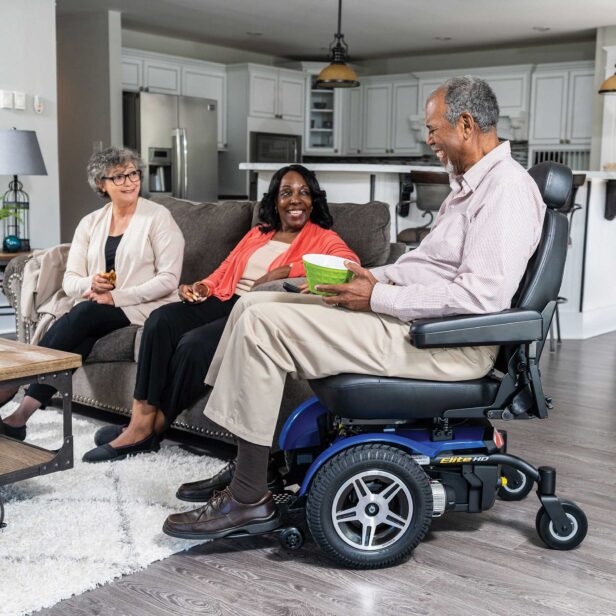 a person using a blue pride power chair in a living room.