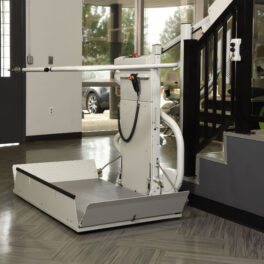 A wheelchair lift is installed next to a stairway, featuring a platform and control panel, providing accessibility to users.