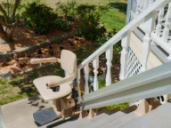 A stair lift is installed on an outdoor staircase, allowing for easier access between different levels of a garden area.