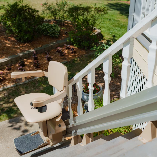 A stair lift is installed on an outdoor staircase, allowing for easier access between different levels of a garden area.