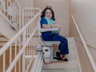 a woman using a bruno elite curved stairlift.