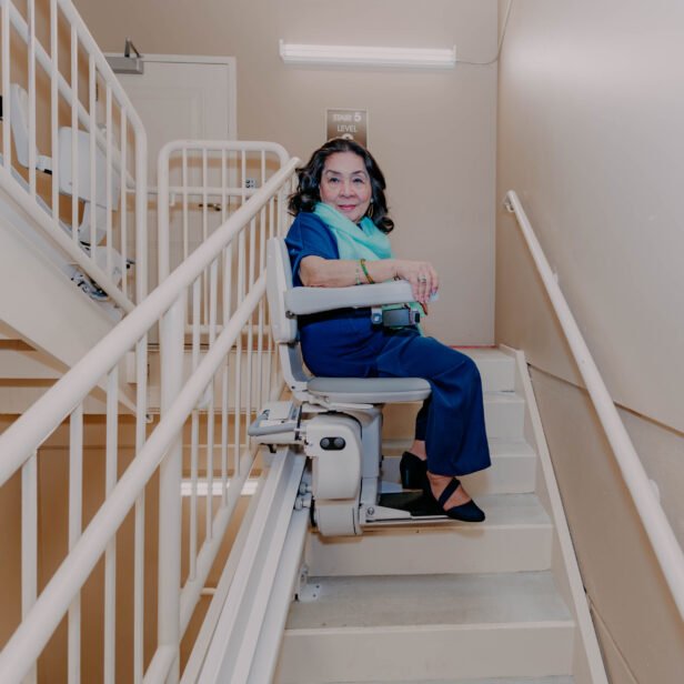 a woman using a bruno elite curved stairlift.