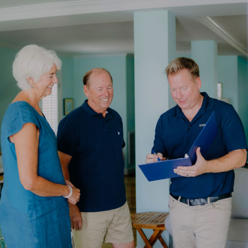 Three people having a conversation indoors as part of a 101 Mobility consultation; one is writing on a clipboard while the other two look on.