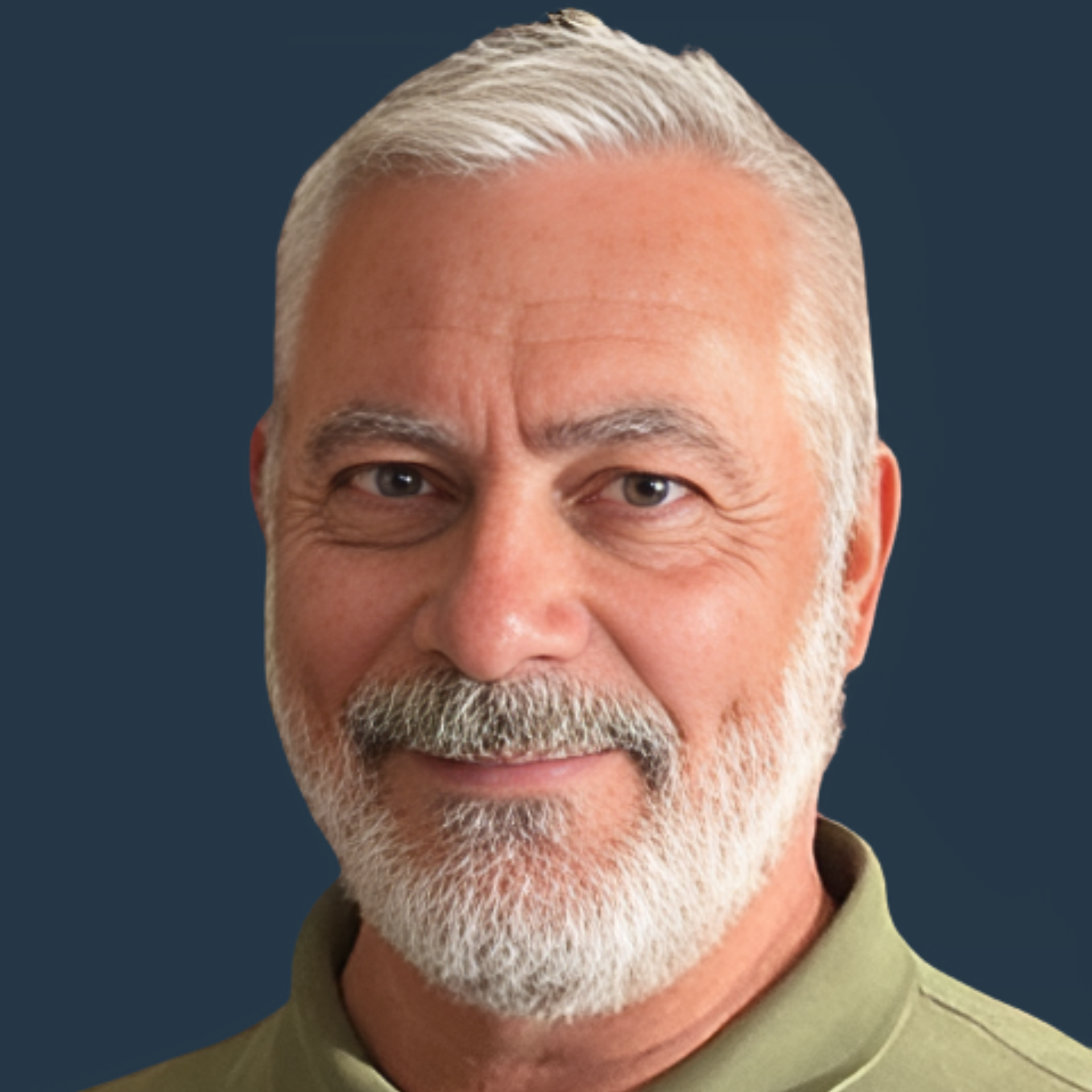 A bearded man with short, gray hair and a green shirt smiles against a plain dark blue background.