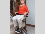 a woman using a staying home indoor stairlift.