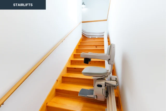 A stairlift is installed on a wooden staircase with white walls.