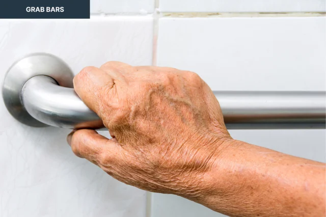 A hand grips a stainless steel grab bar against a tiled wall.