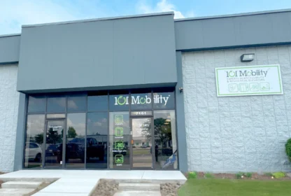 Exterior view of a 101 Mobility store, featuring large glass doors and green signage on a gray building.