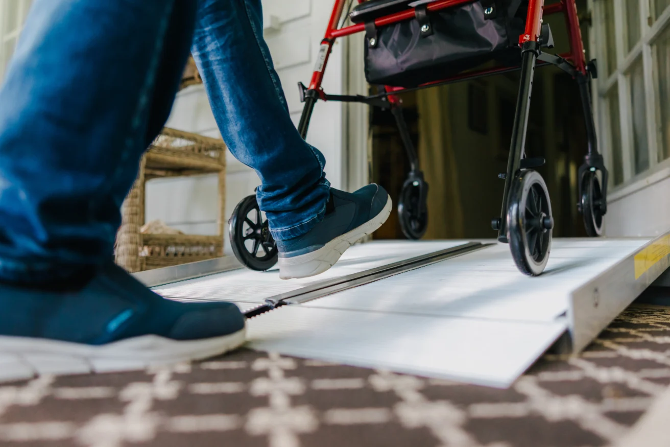 A person using a mobility aid approaches a walker on a ramp inside a building.