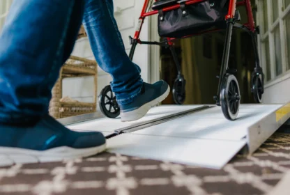 A person using a mobility aid approaches a walker on a ramp inside a building.