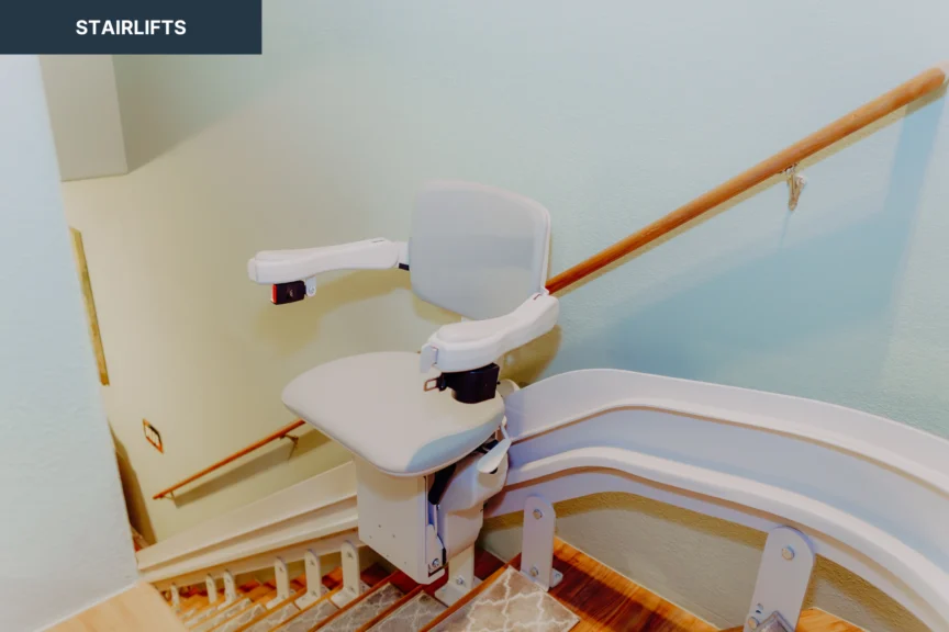 A stairlift installed on a residential staircase, featuring a seat with armrests and a control panel.