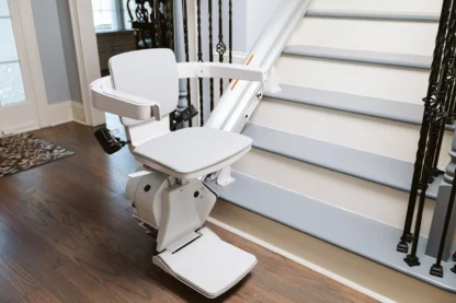 White stair lift on a residential staircase with wooden floors and decorative railings.