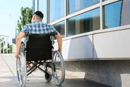 A person in a wheelchair uses a ramp outside a building.