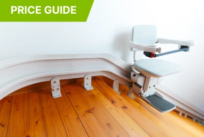 A stairlift installed on a wooden staircase, featuring a grey chair with armrests and footrest, alongside a green label reading "Price Guide.